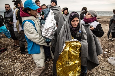 Greece. UNHCR staff member assists refugees on shoreline